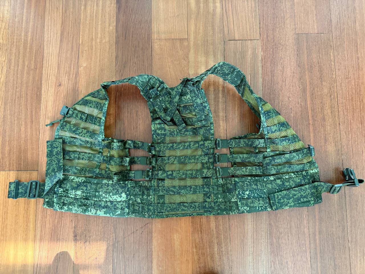 Green camouflage tactical vest on a wooden floor