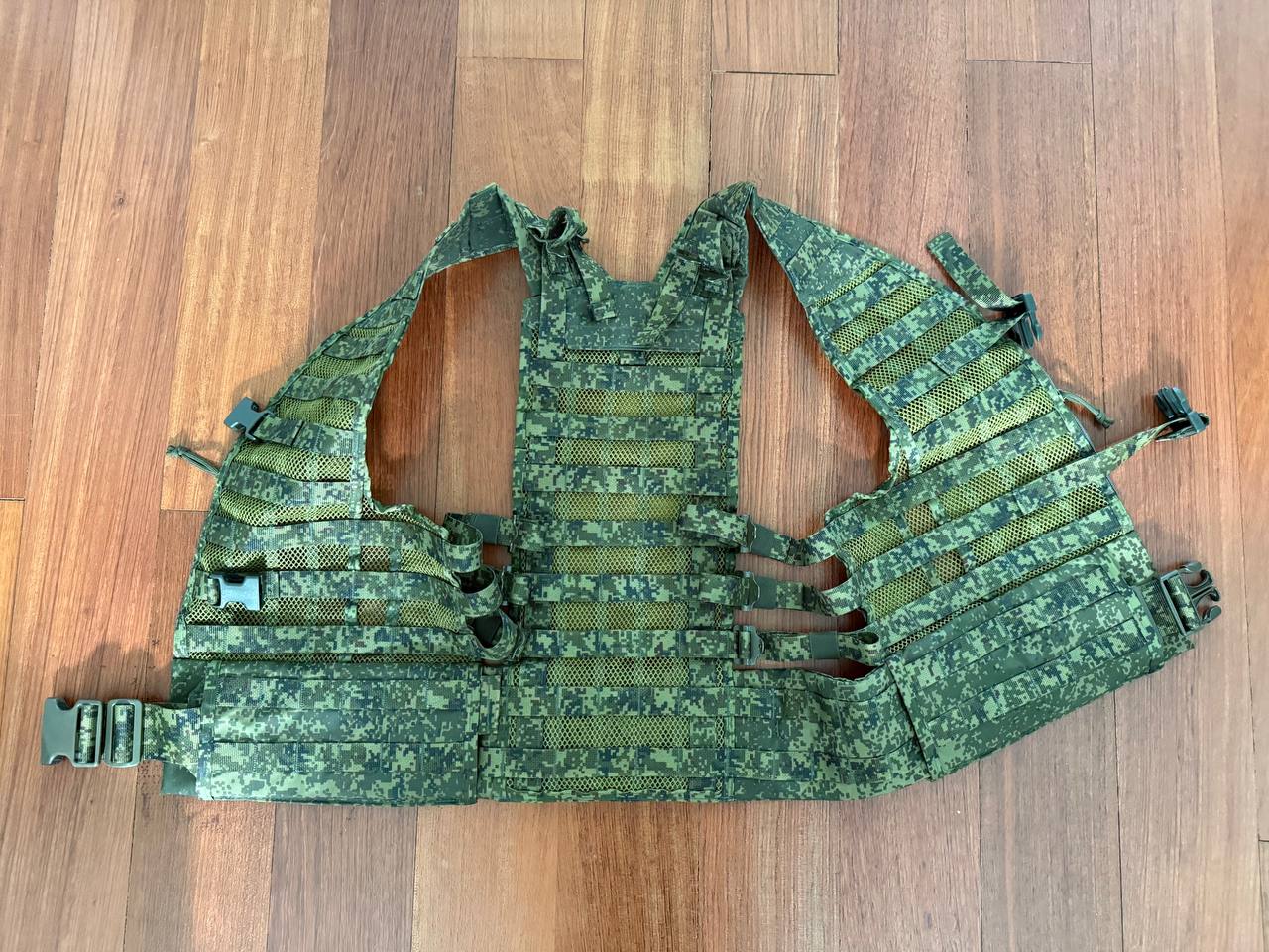 Green camouflage tactical vest on a wooden floor