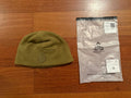 Russian TRIADA-TKO - Demi-season Fleece Hat - Olive - Size 59 displayed on a wooden surface next to its clear plastic packaging featuring the TRIADA logo.