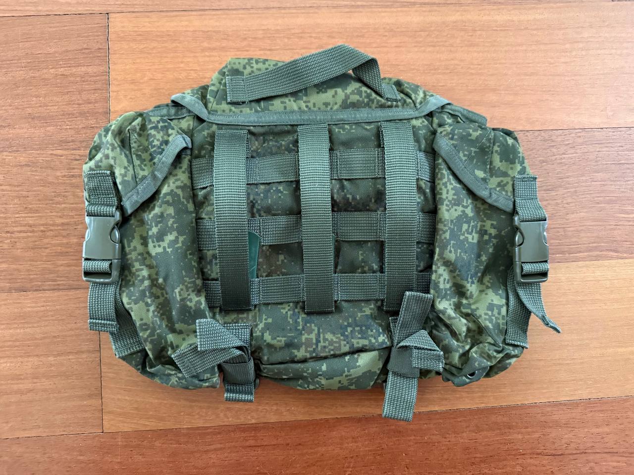 Russian Tekhinkom Buttpack (Old Gen) – EMR (Digital Flora) in green digital camouflage pattern, featuring multiple straps and buckles, displayed on a wooden surface.