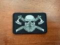 Close-up of a Russian Viking White Toned - Military Patch featuring a skull with a beard and crossed axes on a black background, showcasing detailed embroidery.