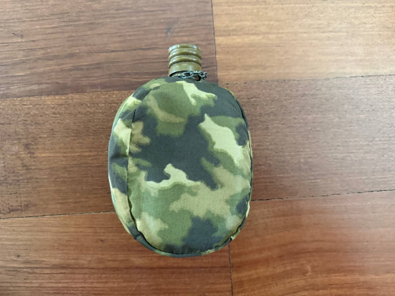 Russian Soviet Army Aluminum Water Flask (Canteen) with Camo Cover placed on a wooden surface, featuring a green and brown camouflage pattern and a metal screw cap.