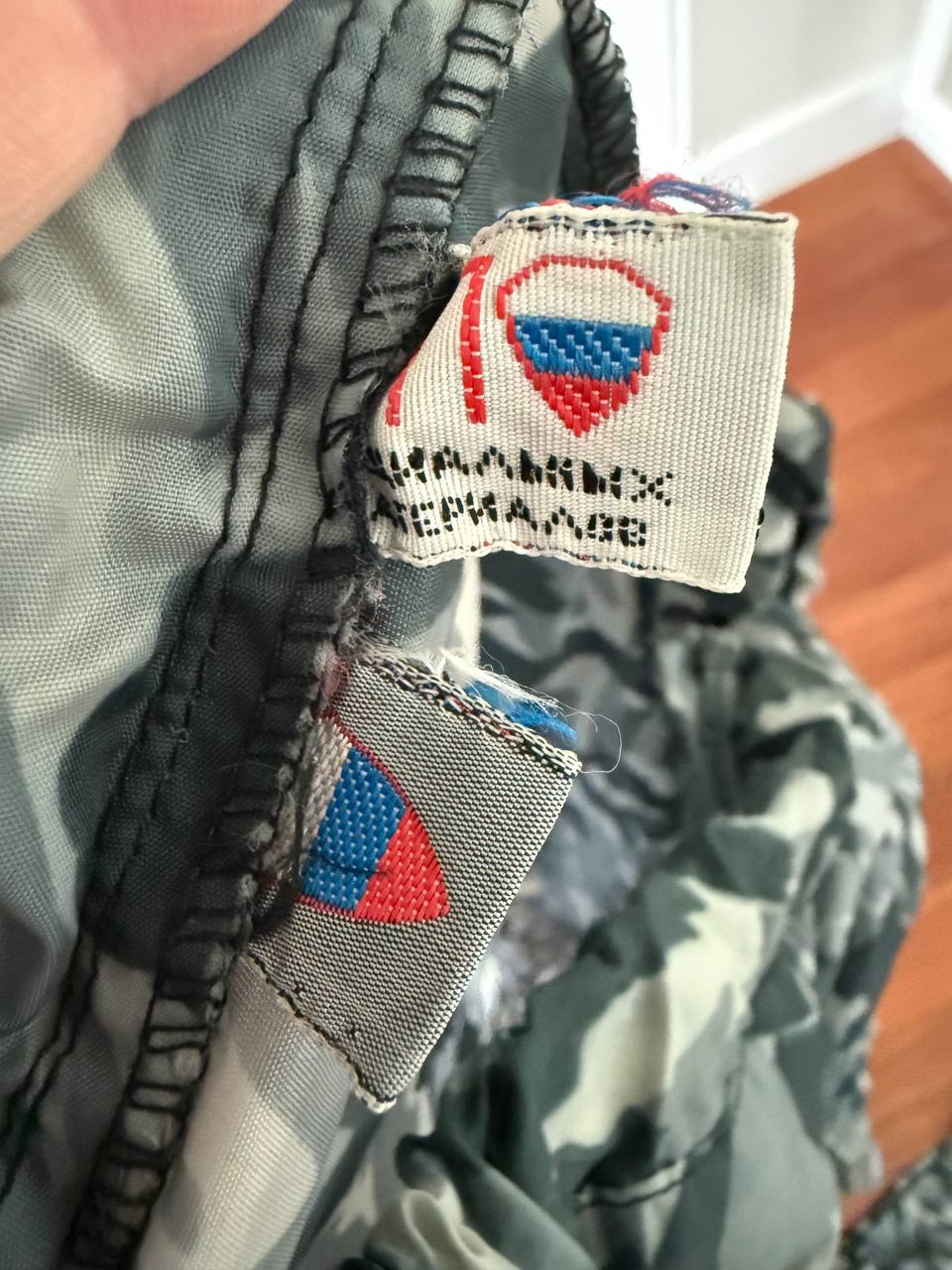 Close-up of fabric tags inside a camouflage garment showing details for the Russian NPO-SM "Sklon" Water-resistant/Windproof Suit – Melted Snow Color, highlighting Russian surplus military apparel.