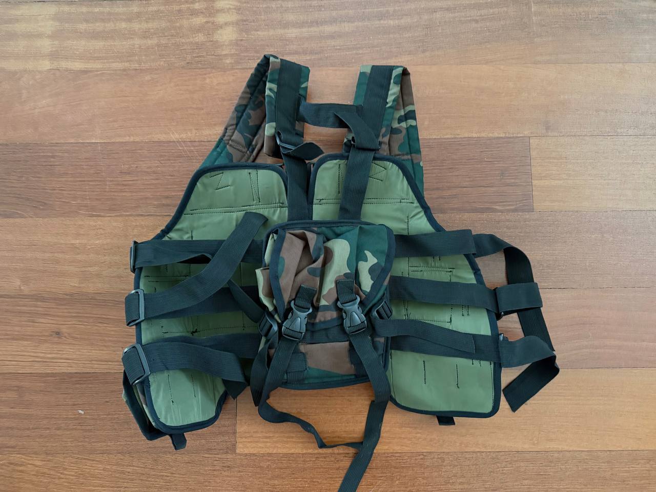 Russian "Vydra" Style Tactical Load-Bearing Vest in camouflage pattern with adjustable black straps and padded sections laid flat on a wooden surface.