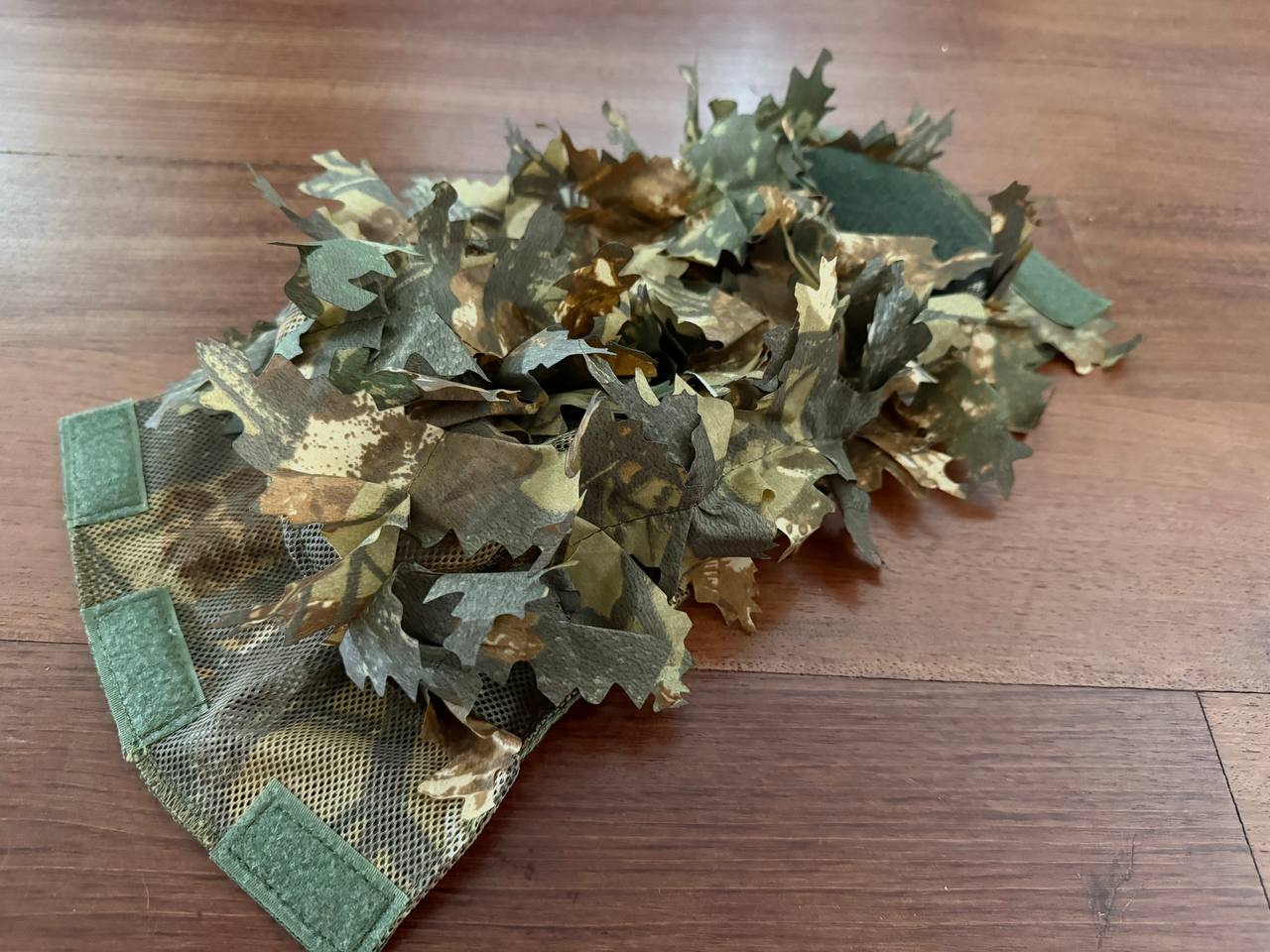 Russian FSB "Autumn" Contract Leaf Helmet Cover featuring realistic autumn leaf camouflage on a fabric base with green attachment straps, designed for tactical use.