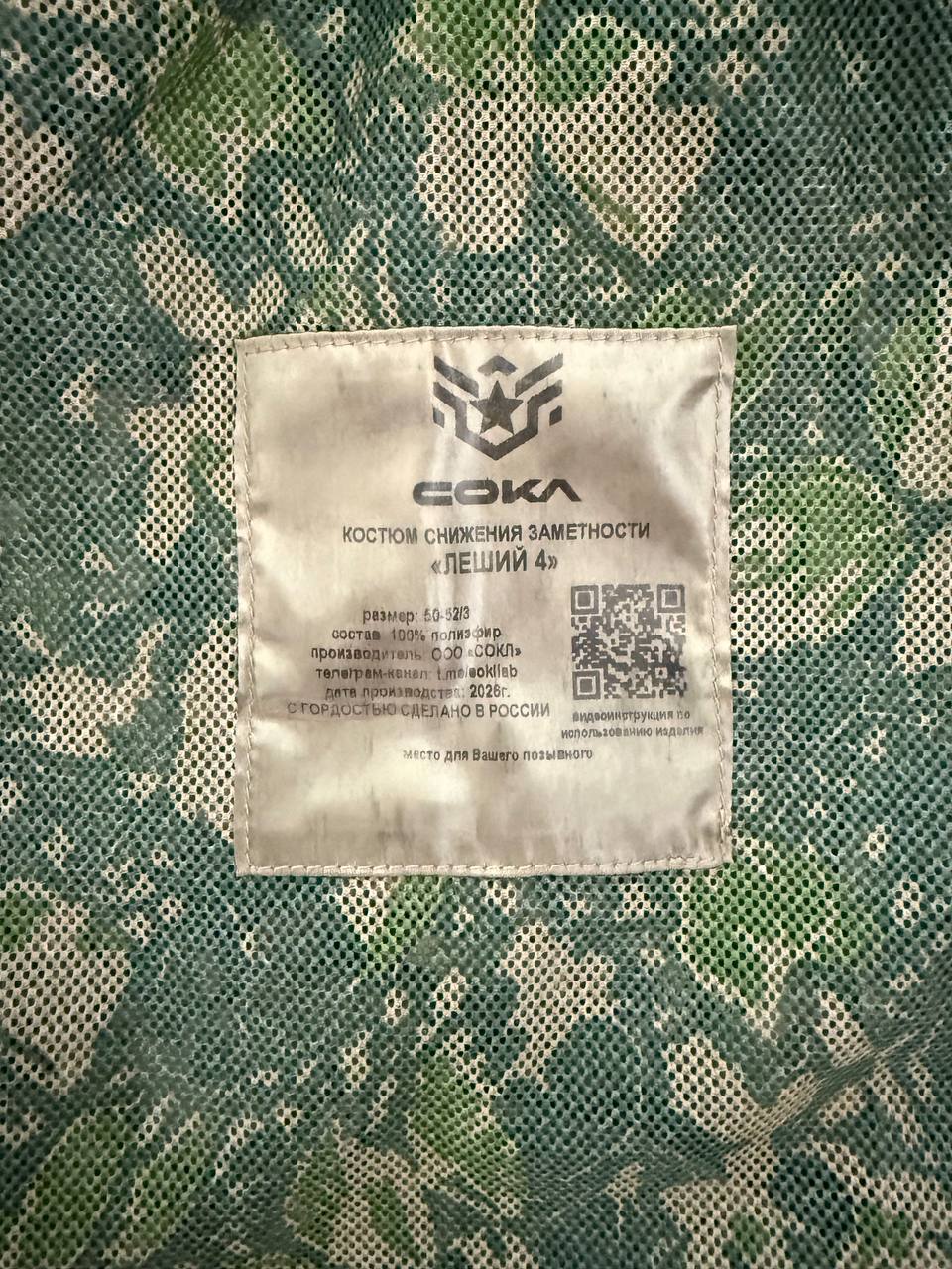 Close-up of a fabric label on a Russian Sokl Leshy 4 Leaf Suit - Summer Pattern - Size 50-52/3, showing care instructions and camouflage mesh material.