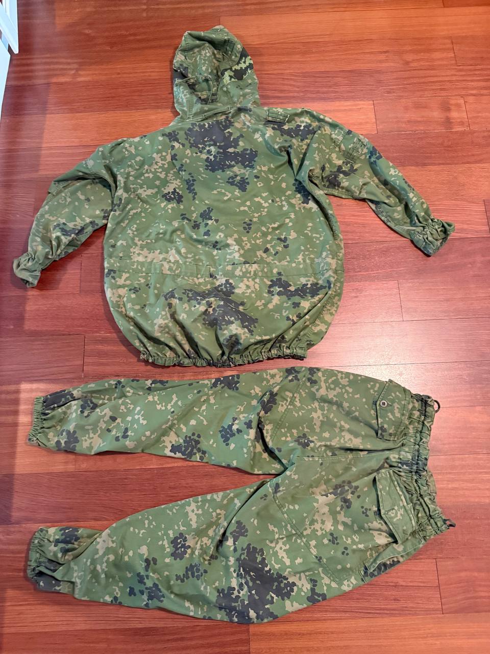 (USED) Russian SSO Partizan Sever Suit - Size 56-58/5 displayed on wooden floor, featuring a green and black digital camouflage pattern typical of Russian surplus military gear.