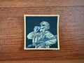 The Tanki Store Russian Skeleton Soldier Drinking Soda Design Patch is a military badge featuring a skeleton in combat gear with a rifle and blue soda can, gold border detail, perfect for patch collectors.