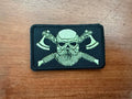 Russian Viking Green Toned - Military Patch featuring a stylized Viking skull with crossed axes on a rectangular fabric patch placed on a wooden surface.