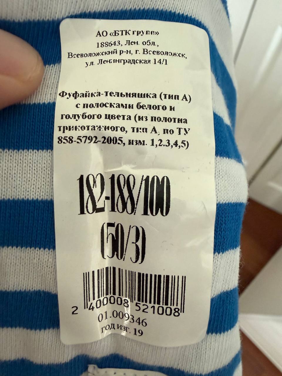 Close-up of a clothing label on a blue and white striped fabric showing details for Russian BTK Group Military Telnyashka (Long Sleeve) - Size 50/3 with manufacturing information and barcodes.
