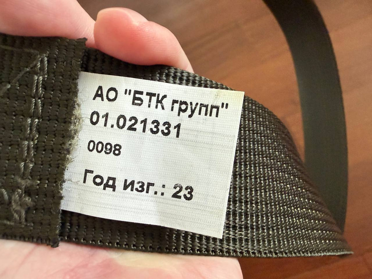 Close-up of a hand holding a Russian BTK Group - VKPO 3.0 Tactical Belt – Olive Drab, showing the product’s label with manufacturing details on the sturdy woven material.
