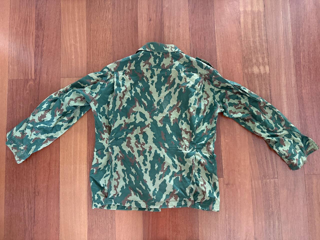 Back view of a Russian VSR-93 Summer Jacket – Size 52/4 featuring classic green, brown, and tan camouflage pattern laid flat on a wooden floor.