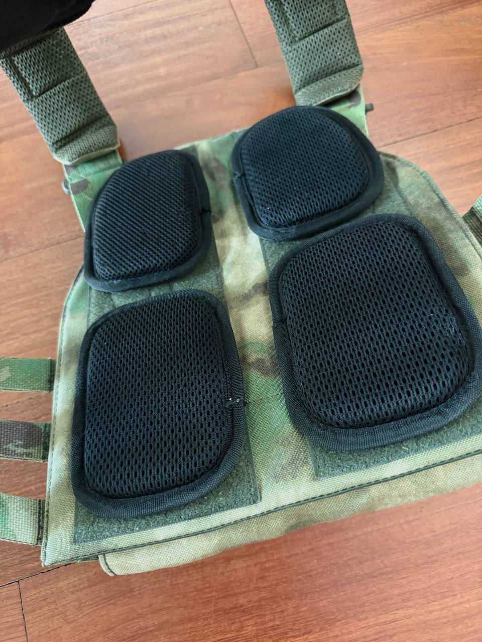 Russian Wartech TV-110 Vest - A-TACS FG Camo - Pre-War Production laid flat on a wooden surface showing padded black mesh sections and adjustable shoulder straps in camouflage pattern.