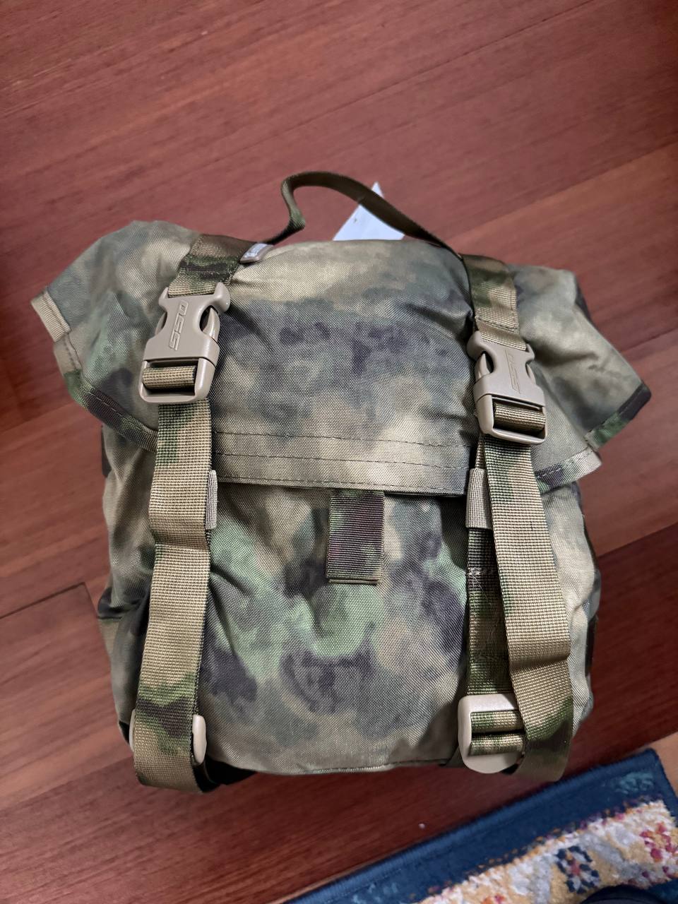 Camouflage backpack on a wooden floor