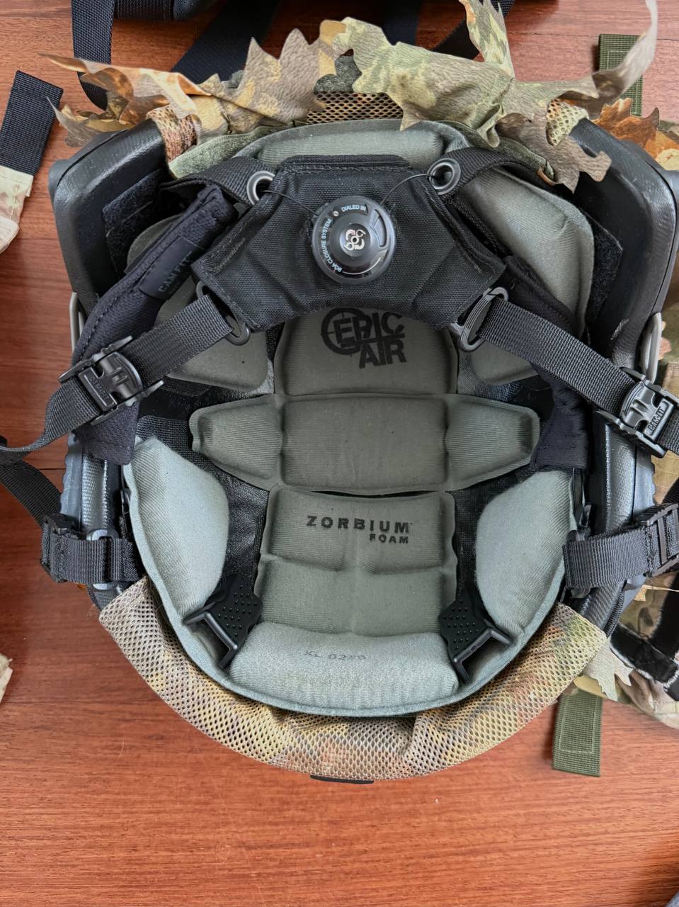 Interior view of the Russian LSHZ 1+ Helmet Size 2 + Team Wendy Upgrade + FSB Contract Leaf Cover showing Zorbium foam padding and adjustable black suspension system on a wooden surface.