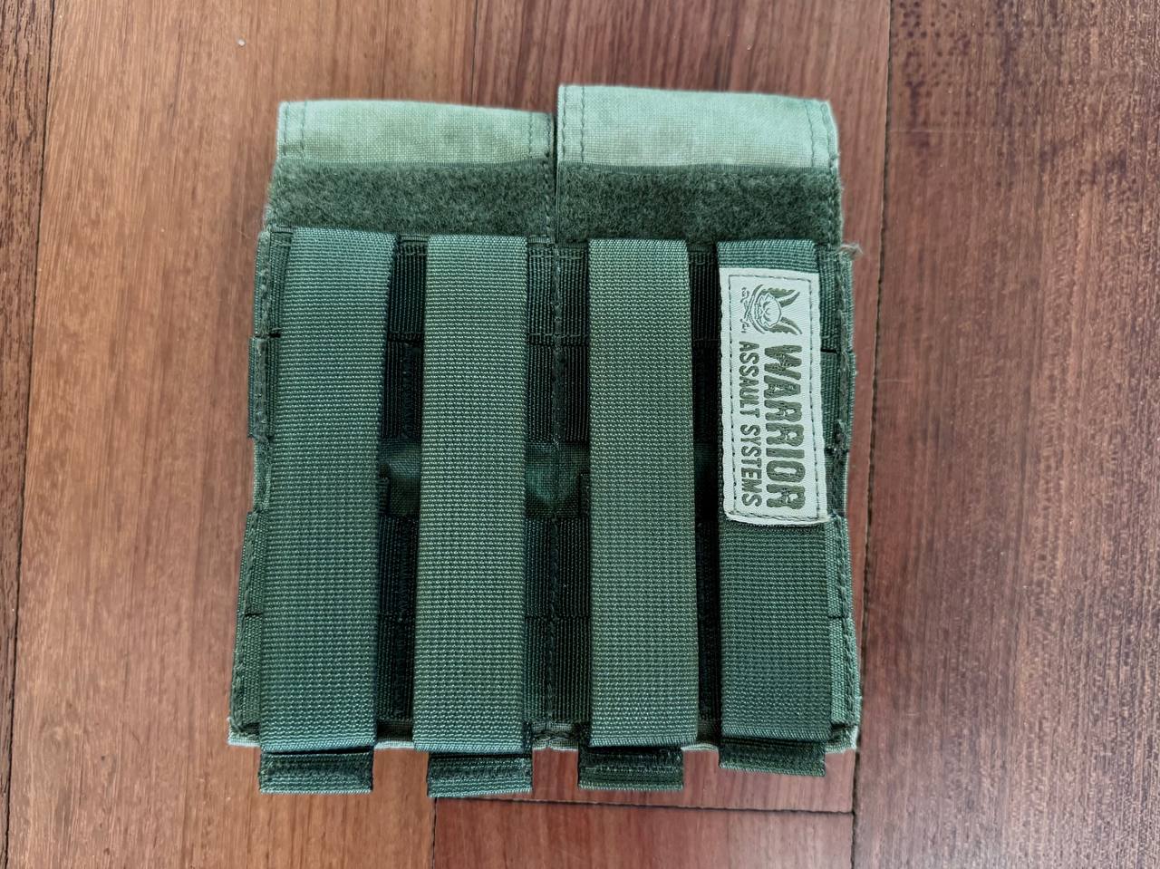 Warrior Assault Systems 4-Cell Mag Pouch - A-TACS FG Camo - Russian Style with four vertical straps for secure attachment, shown on wooden surface.