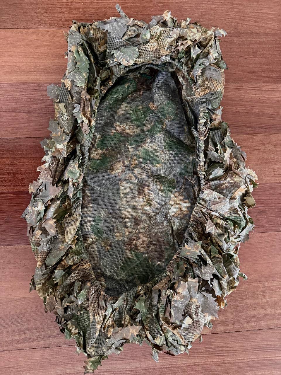 Russian Sokl Leaf Backpack Cover (60L) - Autumn Pattern laid flat on wooden surface, showcasing detailed camouflage fabric with textured leaf design for outdoor concealment.