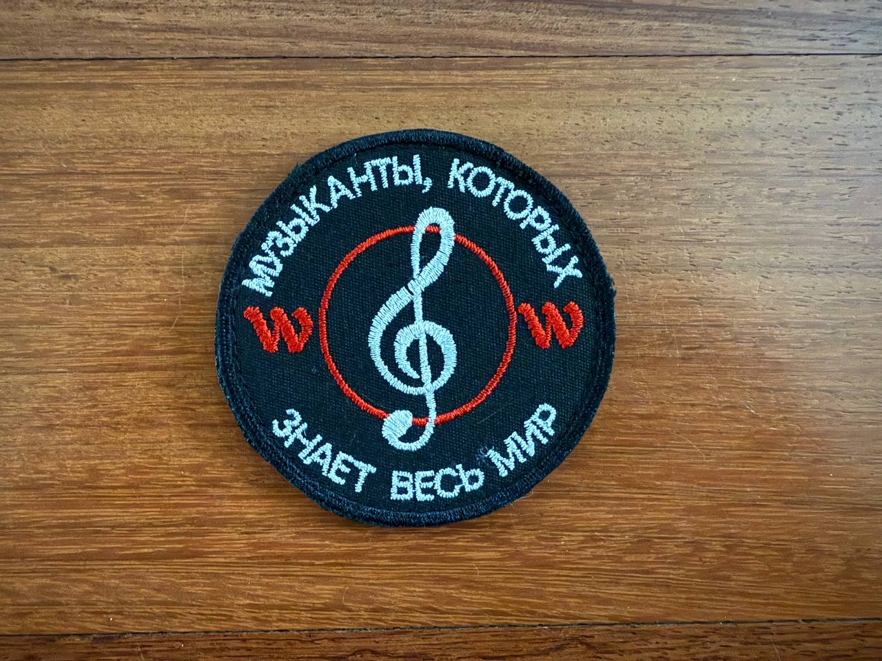 The PMC Wagner Badge from Tanki Store is a round embroidered patch on wood, featuring a white treble clef, red soundwave symbols, and Russian text. Purchase sets to collect multiple Russian Army military patches.