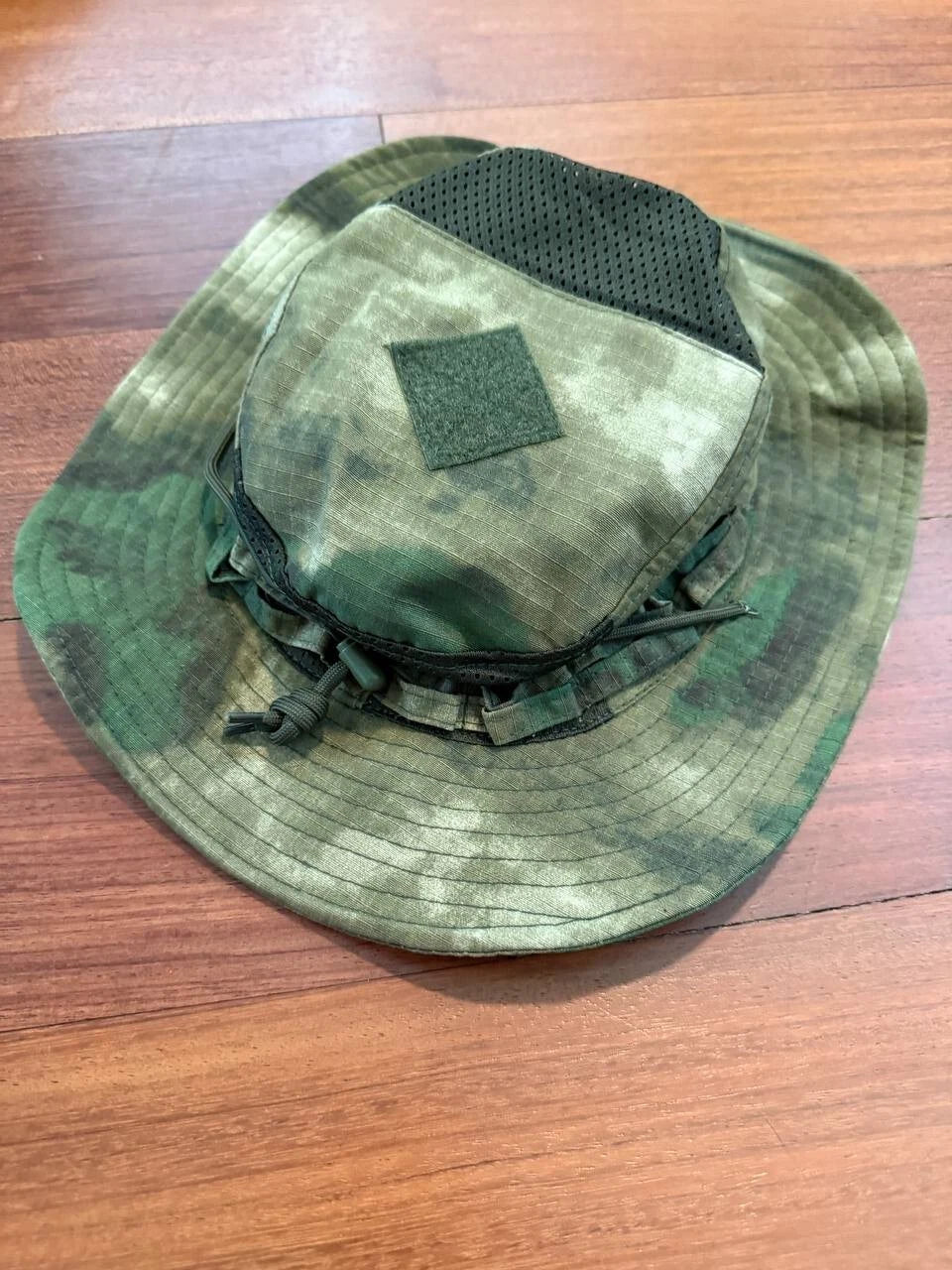 Green camouflage panama hat with a patch on a wooden surface